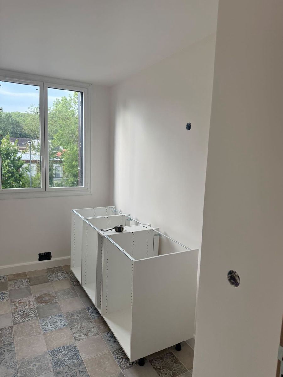 Salle de bain rénovée à Marly-le-Roi : murs blancs, sol effet carreaux de ciment et meubles vasques en cours de pose