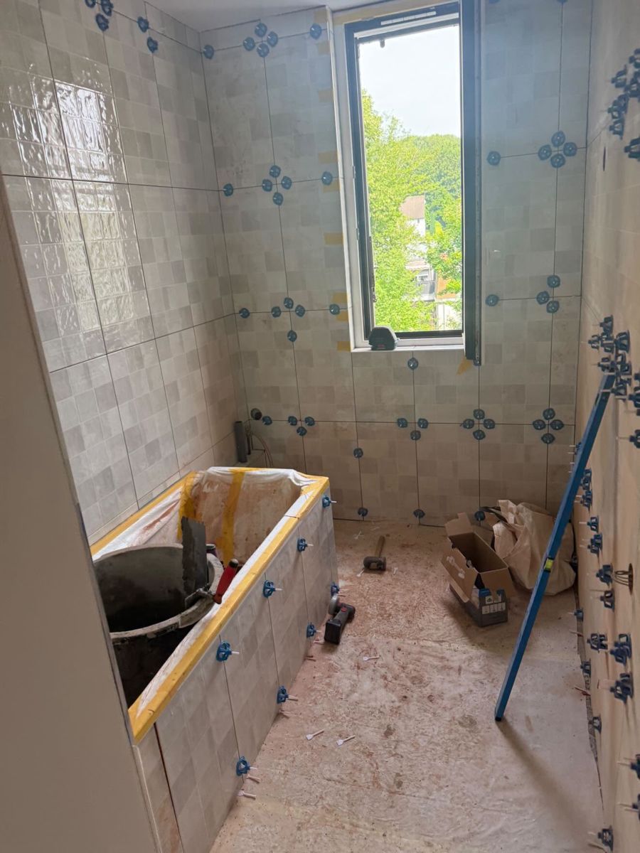 Ancienne salle de bain à Marly-le-Roi avant rénovation : carrelage blanc à motifs bleus et baignoire d'origine